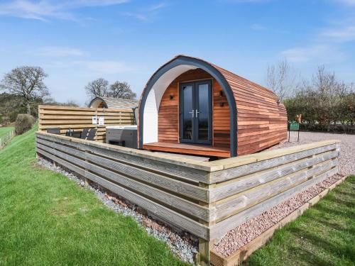 a tiny house with an arched window on a deck at Squirrels Retreat - Uk46127 in Nesscliffe