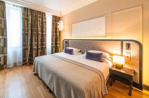 a bedroom with a large bed with purple pillows at Hotel Le Mathurin in Paris