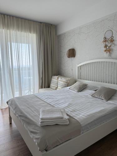 a white bed in a bedroom with a large window at Blaxy del Mar Studio Olimp in Olimp
