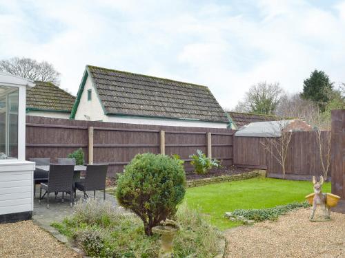 a backyard with a wooden fence and a table and chairs at Oak Lodge in Longham
