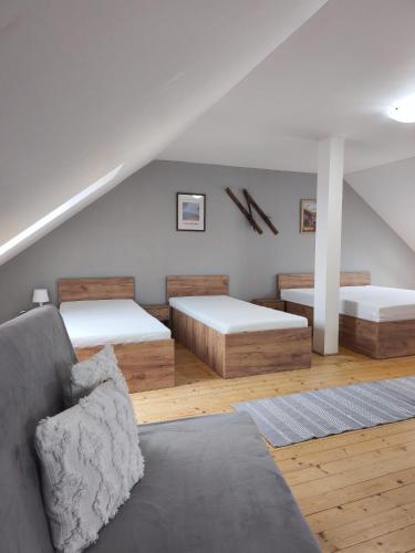 a attic room with two beds and a couch at Apartman Glacier in Tatranska Strba