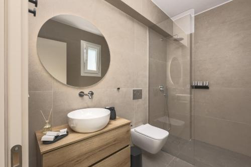 a bathroom with a sink and a toilet and a mirror at Estia Villas Naxos in Naxos Chora