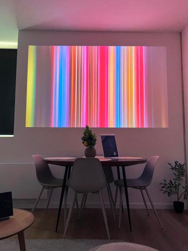a table with chairs and a colorful painting on the wall at Voyageur - Vidéoprojecteur - Terrasse - 5min gare in Ploumagoar
