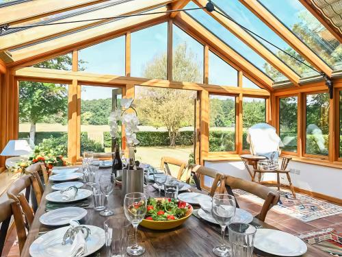 a dining room with a long table in a conservatory at The Granary - Uk52147 in Brundall