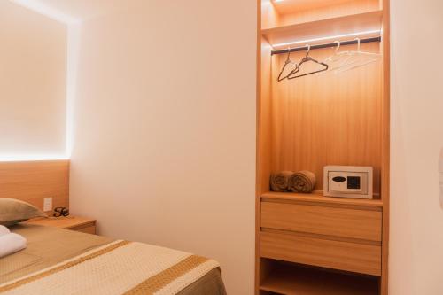 a small bedroom with a bed and a microwave at Apartamento Bitú in Fortaleza