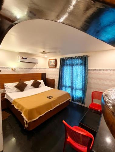 a bedroom with a bed and a red chair at HoTEL SVR ELITE in Vijayawāda