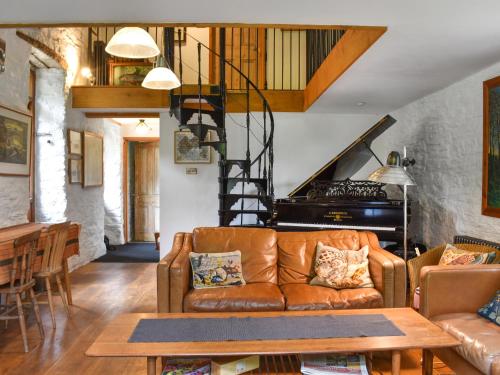 a living room with a couch and a staircase at Swallows Barn in Liskeard