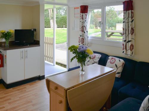 a living room with a vase of flowers on a table at White Moth - Uk12697 in Stalham