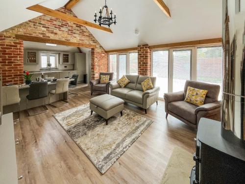 a living room with couches and a kitchen at Rose Blossom Cottage in Benniworth