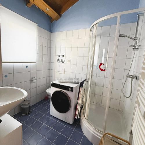 a bathroom with a shower and a washing machine in it at FeWo Mangfall in Bruckmühl