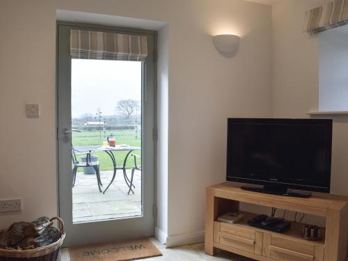 a living room with a tv and a door to a patio at Five Barred Gate Barn in Inglewhite