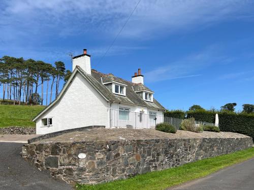 a white house sitting on top of a stone wall at Balnowlart Lodge in Ballantrae