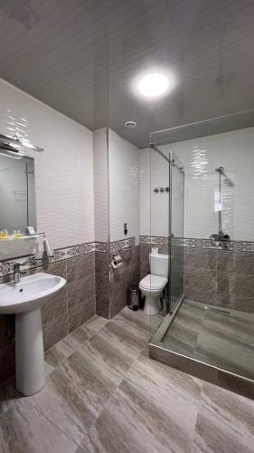 a bathroom with a shower and a toilet and a sink at Art Moderno Hotel in Tashkent