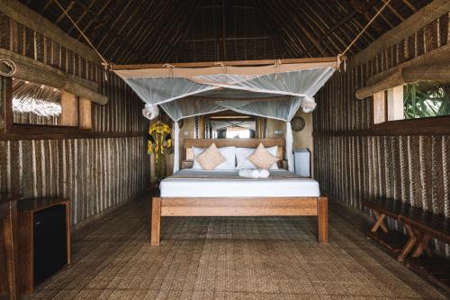 a bed in a room with a canopy at Zanzibar Sunrise at Bandas in Matemwe
