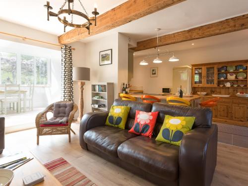 a living room with a leather couch and a kitchen at The Barn - Uk2475 in West Witton