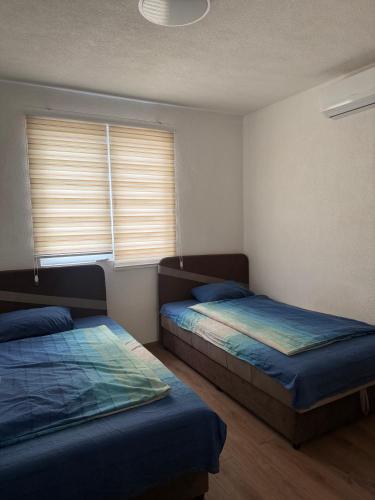 a bedroom with two beds and a window with blinds at Luxury Apartments Sarajevo in Ilijaš