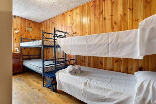 a bedroom with two bunk beds in a wooden wall at Dolomiti Apartment Pinzolo in Pinzolo