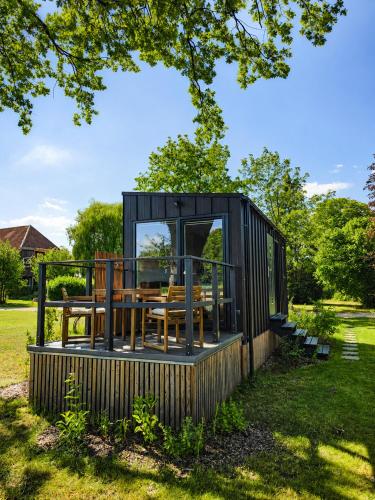 a black tiny house with a deck in the grass at Chalet Oslo in Bleckede