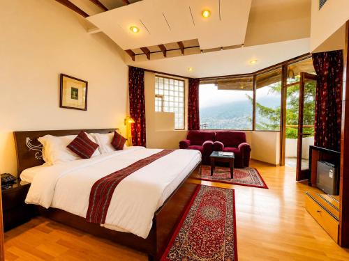 a bedroom with a large bed and a large window at Manuallaya The Resort & Spa in Manāli