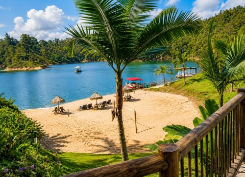 a beach with chairs and umbrellas next to the water at Hotel Pietrasanta Cabañas frente a la Represa Peñol Guatape in Guatapé