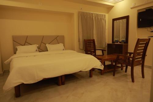 a bedroom with a bed and a table and chairs at Sri Balakrishna Residency in Thiruchendur