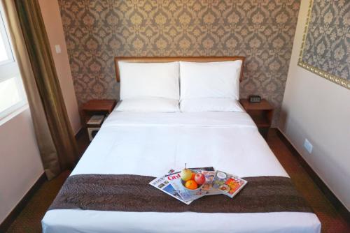a hotel room with a bed with a magazine and fruit on it at Best Western Hotel Causeway Bay in Hong Kong
