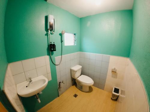 a green bathroom with a toilet and a sink at New Modern Summer House in Moalboal