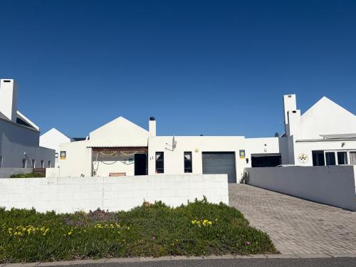 a white house with a fence and a driveway at Sunset Sands in St. Helena Bay