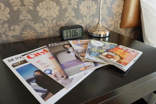 a table with two magazines and a clock on it at Best Western Hotel Causeway Bay in Hong Kong