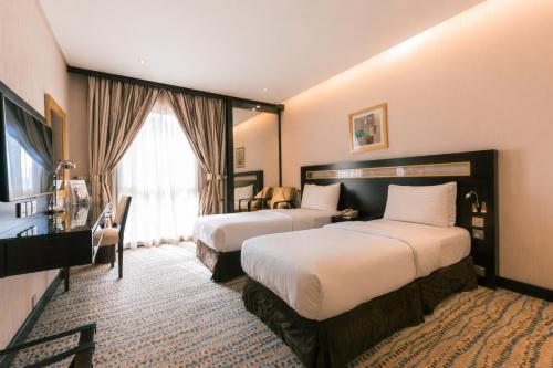 a hotel room with two beds and a window at Golden Tulip Bahrain in Manama