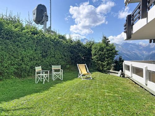two chairs and a table on the lawn of a house at Apartment Hauts De Nendaz B OP by Interhome in Nendaz