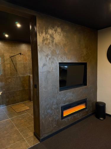 a bathroom with a fireplace and a tv on a wall at 4 Rooms Pixel A in Herzebrock