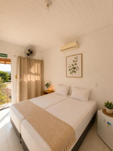 a bedroom with a large white bed and a window at Pousada Escarpas in Capitólio