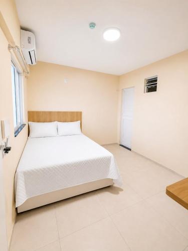 a bedroom with a white bed and a window at Pousada Milagres in Canindé