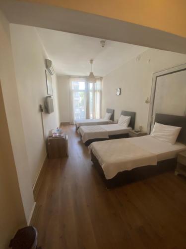 a room with three beds and a window at Toprak otel pansiyon in Akhisar