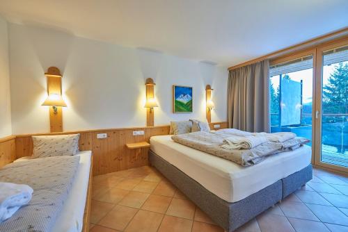 a bedroom with two beds and a large window at Appartement Hotel Sonneck in Königsleiten