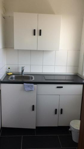 a kitchen with white cabinets and a sink at Messeapartment Köln in Cologne