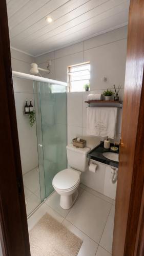 a bathroom with a toilet and a glass shower at Pousada Horizontes de Bonito in Bonito