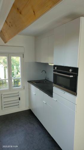 a kitchen with white cabinets and a sink and a window at WhiteHouse Lozère in Palaiseau
