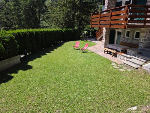 two chairs sitting on the grass near a house at Chalet Villa Bianca in Tesero