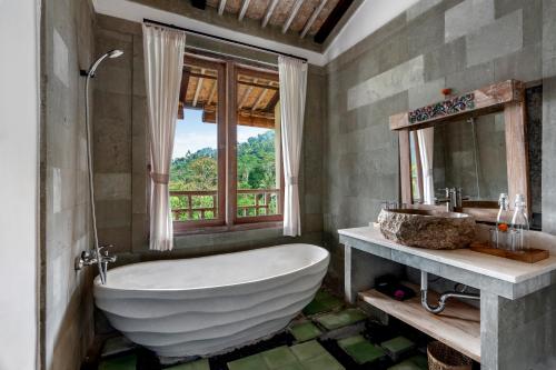 a bathroom with a large tub and a window at ArtVilla Sidemen River in Sidemen