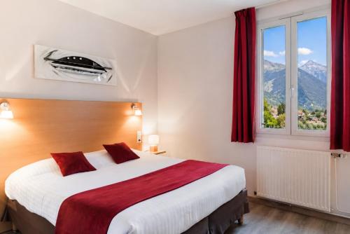 a bedroom with a large bed with a large window at Carré Py' Hôtel in Bagnères-de-Bigorre
