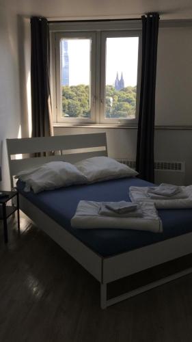 a bed in a room with two windows at Messeapartment Köln in Cologne