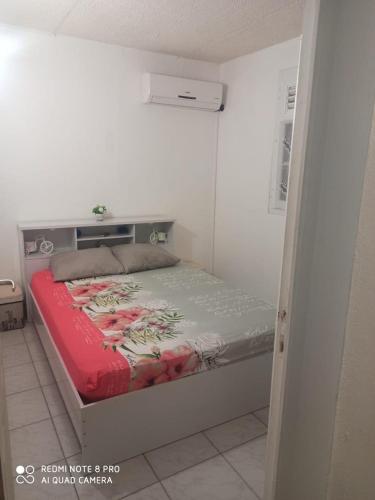 a small bedroom with a bed with a red blanket at F2 F3 Marjo tranquillity in Le Carbet