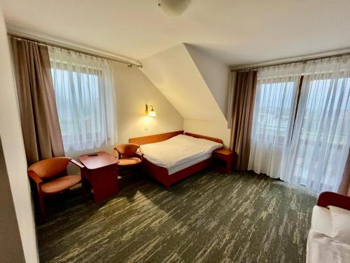 a hotel room with a bed and chairs and windows at LUNA Baltica in Rewal