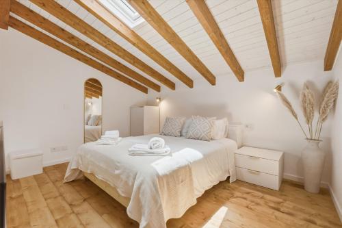 a white bedroom with a large bed and wooden ceilings at Casinha do Beco in Lagos