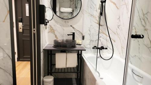 a bathroom with a sink and a tub and a mirror at Star Champs-Elysées in Paris