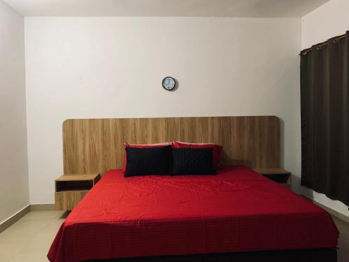 a bedroom with a red bed with a clock on the wall at Hostal Monte Verde in Zaragoza