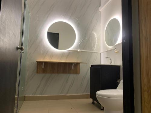 a bathroom with a toilet and a sink and two mirrors at Hostal Monte Verde in Zaragoza
