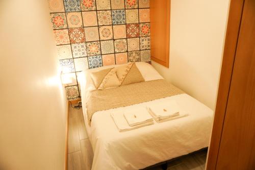 a small bed in a small room with a tiled wall at VIELA Guest House T1 in Barcelos